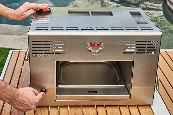 Man pushing igniter button on Schwank Grill